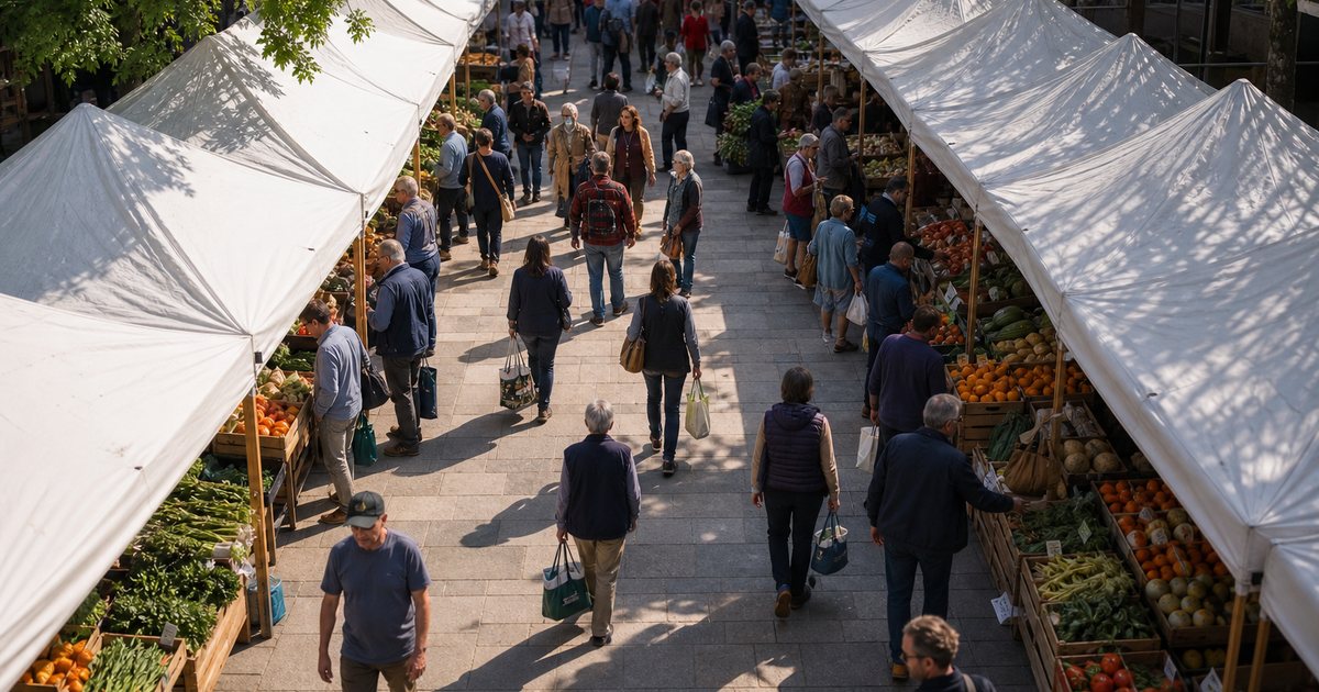 Overhead view of a farmers market in a town square with two rows of white canopy tents forming a horseshoe, shoppers walking the aisle with tote bags, produce crates visible, sunny morning