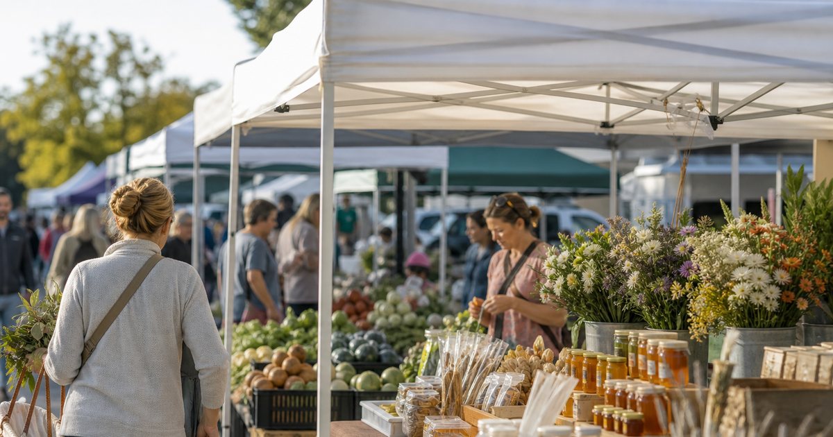 Small-town farmers market with a dozen stalls showing varied products, a honey table beside a flower stand and a vegetable stall, shoppers browsing, morning sun on the tents
